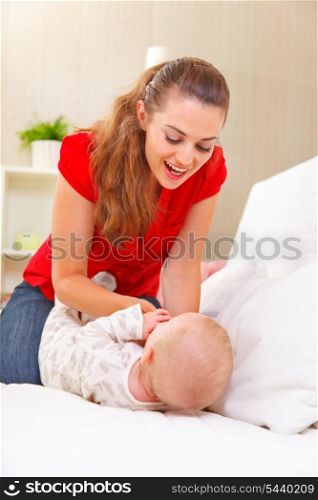 Young mother playing with baby on divan