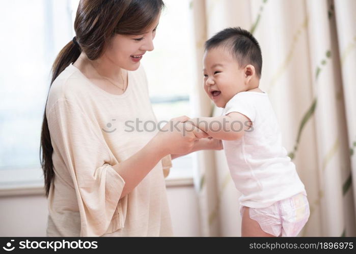 Young mother playing with her baby on the bed