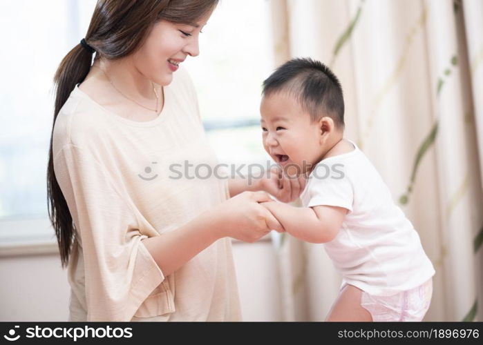 Young mother playing with her baby on the bed