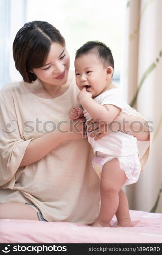 Young mother playing with her baby on the bed