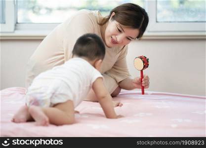 Young mother playing with her baby on the bed