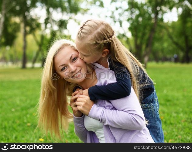 Young mother playing with little daughter in green summer park