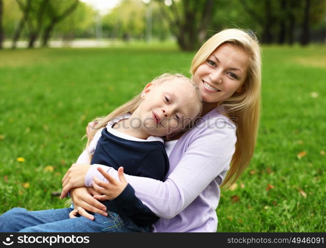 Young mother playing with little daughter in green summer park