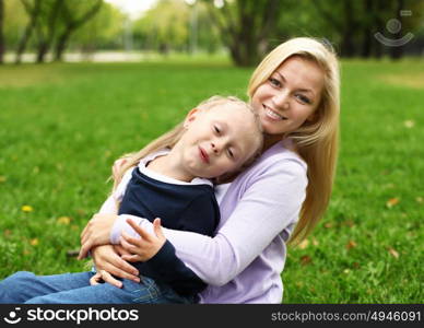 Young mother playing with little daughter in green summer park