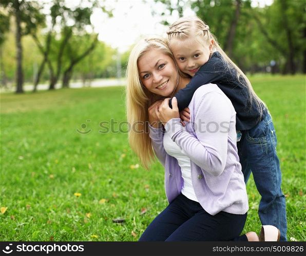Young mother playing with little daughter in green summer park