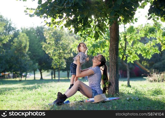 Young mother raising baby on hands up in the air