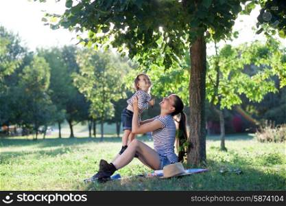 Young mother raising baby on hands up in the air