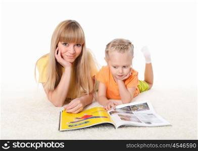 young mother reading a book to her little daughter on the carpet
