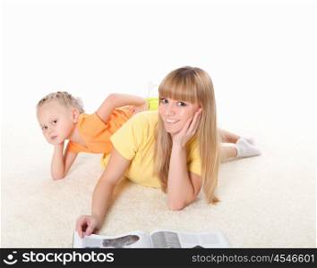 young mother reading a book to her little daughter on the carpet
