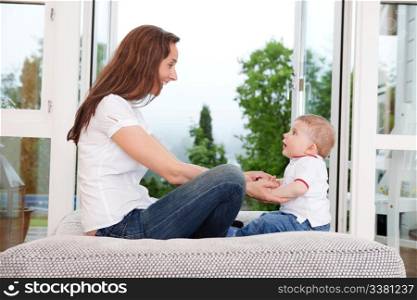 Young mother sitting on couch and looking at innocent child
