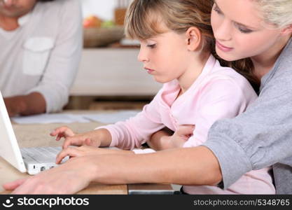 young mother teaching her daughter how to use computer