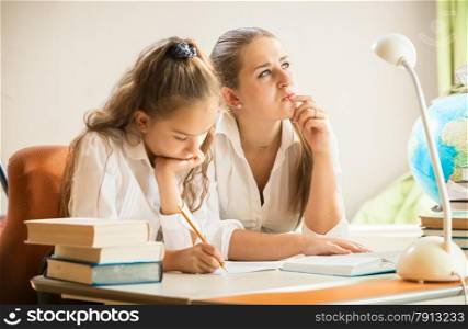 Young mother trying to solve complicated exercise with little daughter