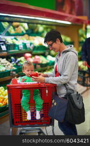 young mother with baby in shopping mall supermarket store buying food and grocery