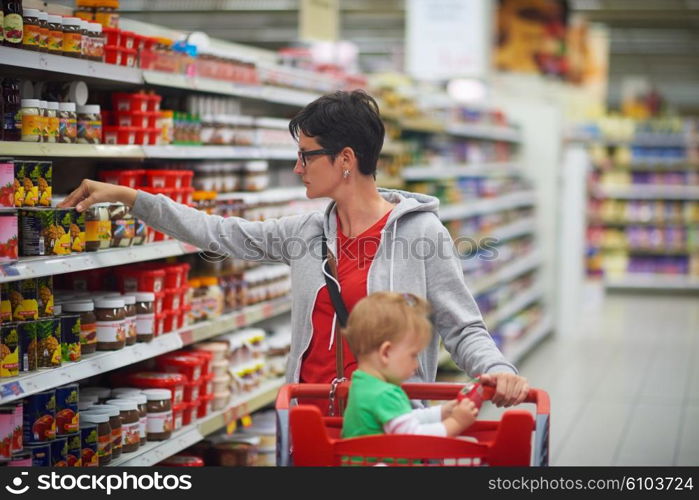 young mother with baby in shopping mall supermarket store buying food and grocery