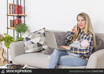 young mother with baby talking phone using laptop