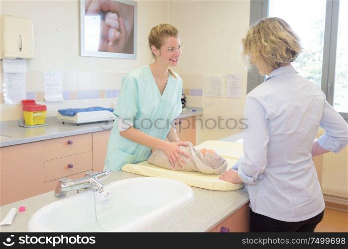 young mother with baby talking with friendly pediatrician doctor