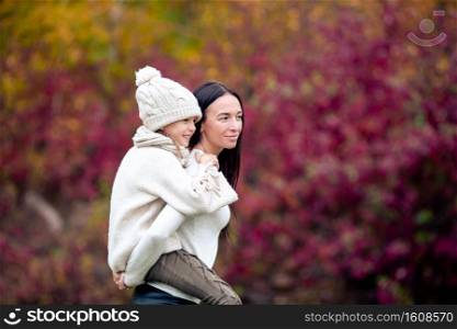 Young mother with cute little girl in autumn park on sunny day. Family enjoy warm weather at september day. Little girl with mom outdoors in park at autumn day