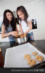 Young mother with daughter in kitchen preparing cookies