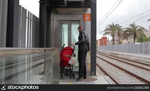Young mother with her baby in a pram is entering the elevator at the Barcelona railway station.
