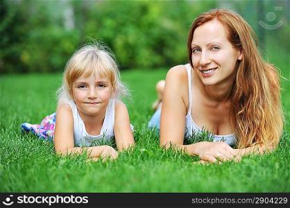 young mother with her daughter lie on grass . summer day.