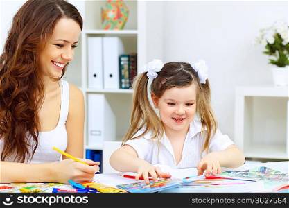 Young mother with little daughter studying at home