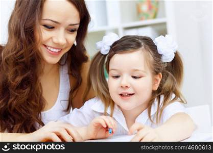 Young mother with little daughter studying at home