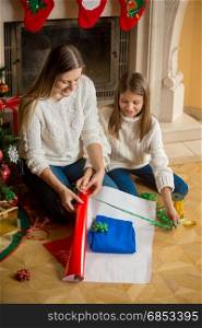 Young mother wrapping Christmas presents with her daughter