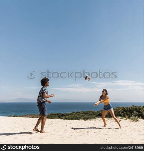 young multicultural couple playing volleyball beach