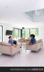 Young multiethnic couple sitting on a sofa in the luxury living room, using a tablet computer