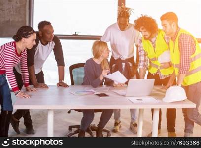 young multiethnic team of business people in group  checking documents and business workflow using tablet computer with sunlight through the windows on construction site at new startup office