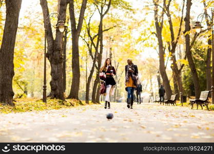Young multiracial friends walking around autumn park, talking and carry coffee to go in the hands