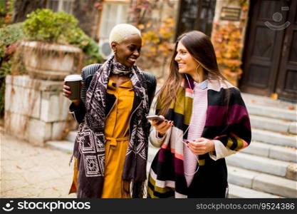 Young multiracial friends walking around the town, talking and carry coffee to go in the hands