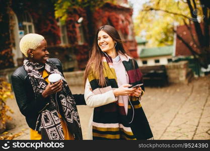 Young multiracial friends walking around the town, talking and carry coffee to go in the hands