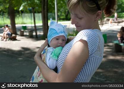 Young mum in park with the small child on hands