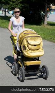 Young mum on walk with a baby carriage