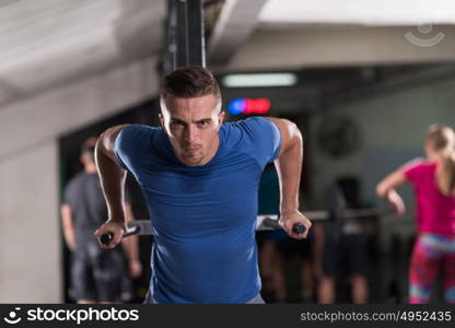 young muscular bodybuilder working out in gym doing exercises parallel bars Concept sport