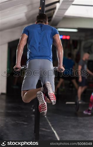 young muscular bodybuilder working out in gym doing exercises parallel bars Concept sport