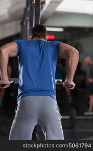 young muscular bodybuilder working out in gym doing exercises parallel bars Concept sport