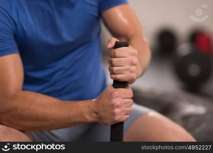 young muscular man after workout at gym with hammer and tractor tire with a focus on hands