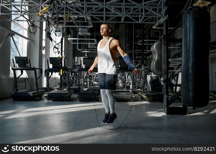 Young muscular man doing active training with jumping rope. Athletic male bodybuilder using gym equipment for strong workout cardio exercise. Young muscular man doing active training with jumping rope gym equipment