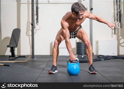 Young muscular man training with kettlebells. High quality photo. Young muscular man training with kettlebells.
