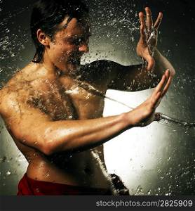 Young muscular man under the rain. High contrast effect.