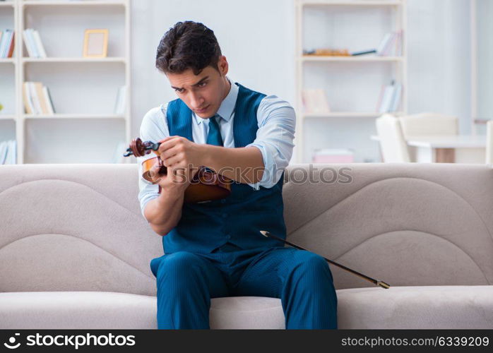 Young musician man practicing playing violin at home