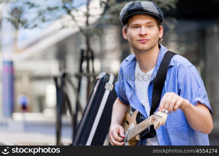 Young musician with guitar in city. Portrait of young musician with guitar in city