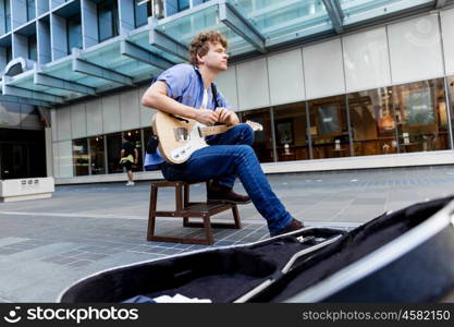 Young musician with guitar in city. Portrait of young musician with guitar in city