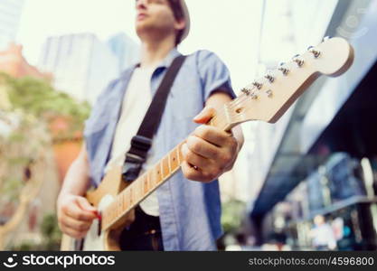 Young musician with guitar in city. Portrait of young musician with guitar in city