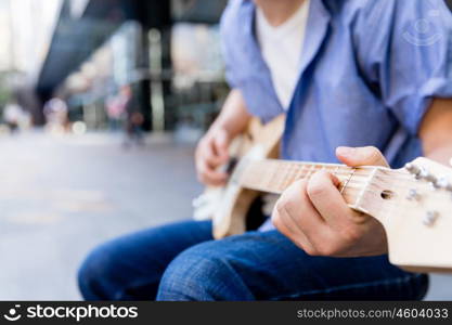 Young musician with guitar in city. Portrait of young musician with guitar in city