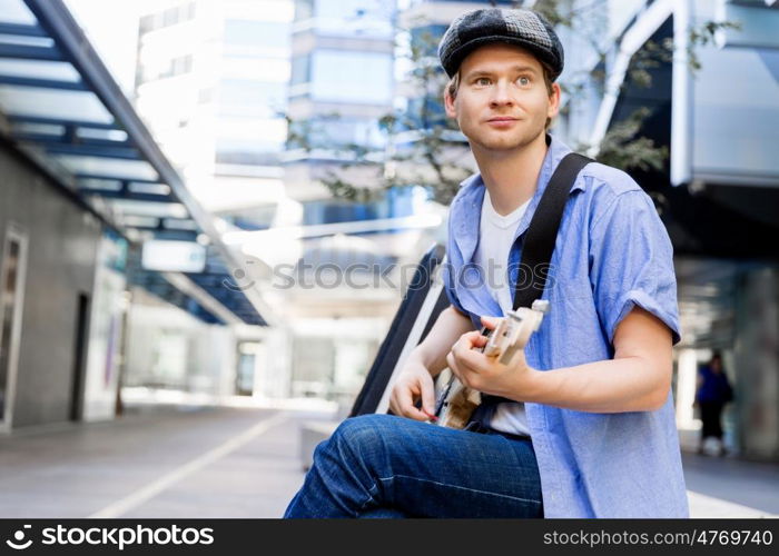 Young musician with guitar in city. Portrait of young musician with guitar in city