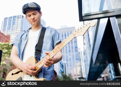 Young musician with guitar in city. Portrait of young musician with guitar in city