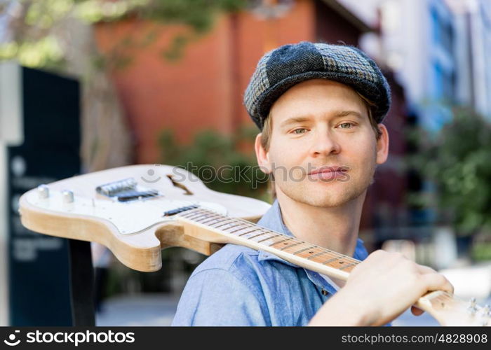 Young musician with guitar in city. Portrait of young musician with guitar in city